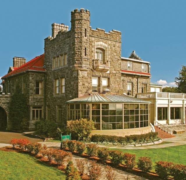 The stone exterior of the Biddle House with a wall of windows overlooking the property.