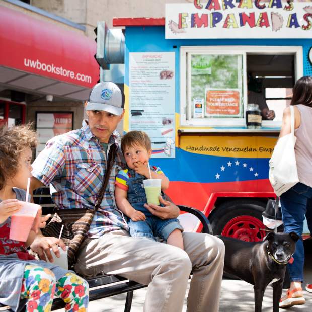 A family sits on a bench enjoying food from one of Madison's many food carts