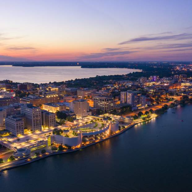 An aerial view of Downtown Madison and the isthmus lit up as dusk approaches