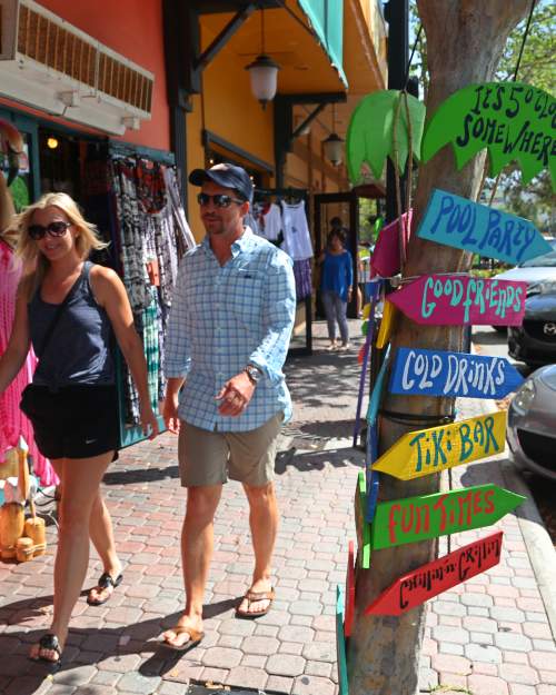 Visitors walk along Main Street in Dunedin, lined with shops and restaurants.