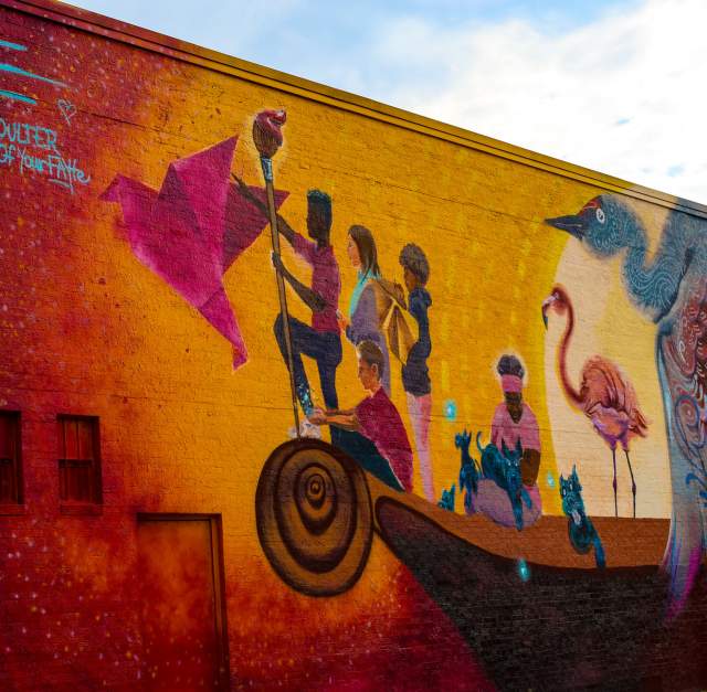 A vivid mural of a young girl leaping across inspiring typography