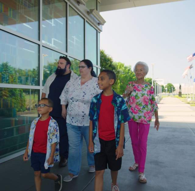 Multi-Generational family visiting Fayetteville's Veterans' Park with the ASOM in the background