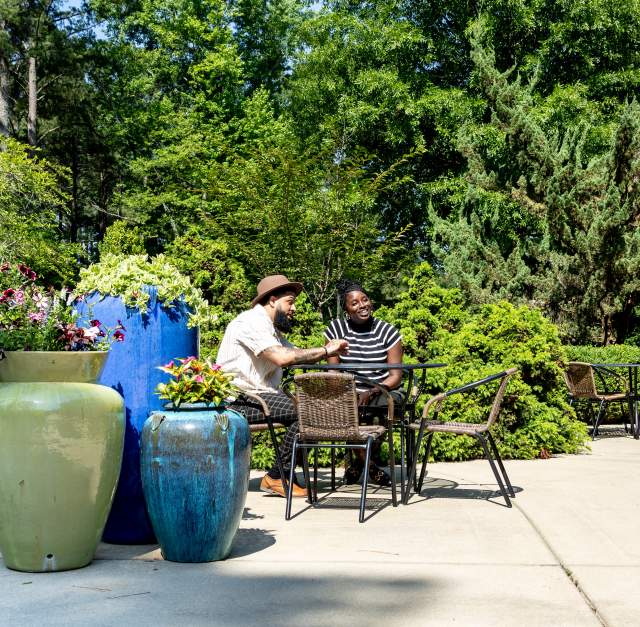 A young couple sitting at a table on the patio outside of Fayetteville's Cape Fear Botanical Garden