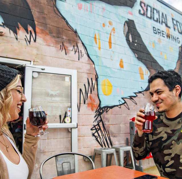 exterior of social fox brewery with large fox mural and man and woman drinking beer