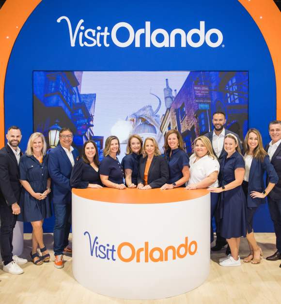 Group of people posing in front of a Visit Orlando trade show booth