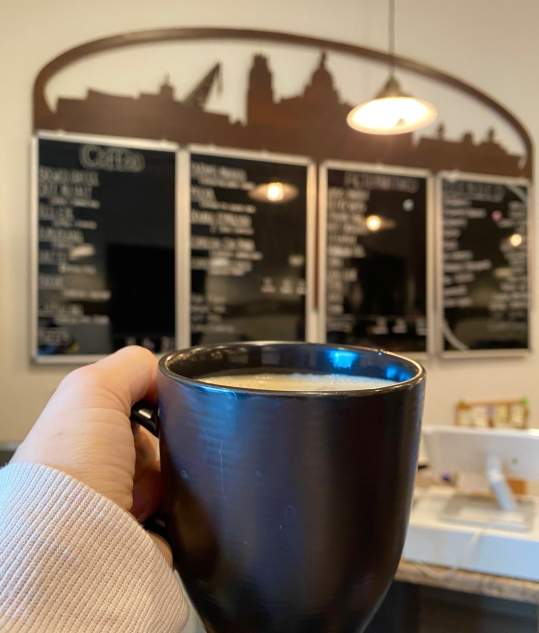 Coffee cup held in front of Manitowoc Coffee menu