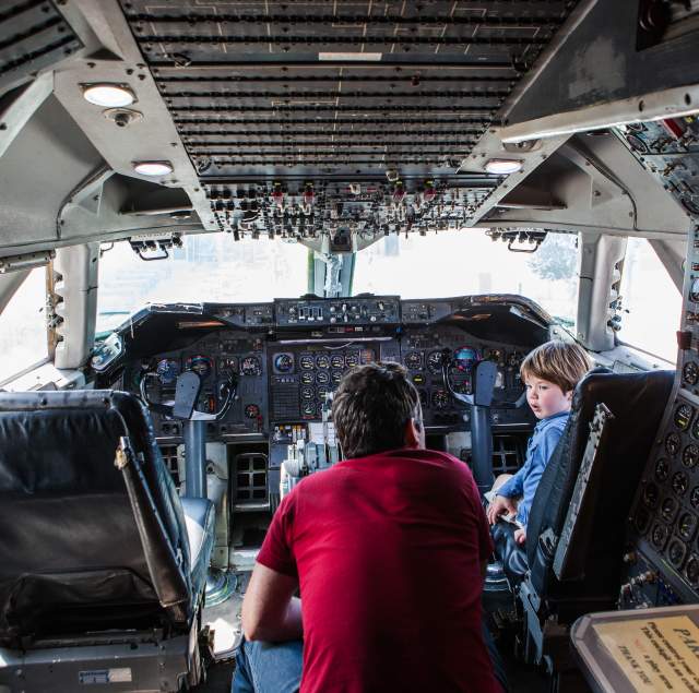 Kid experiencing the flight deck at Hiller Aviation Museum with a tour guide