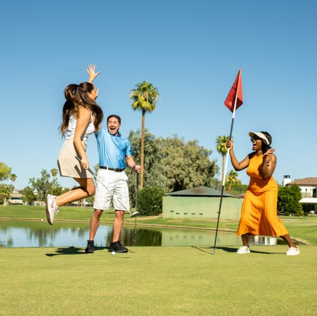 Group jumping and cheering at golfer who putted golf ball into the hole on the San Marcos Golf Course.
