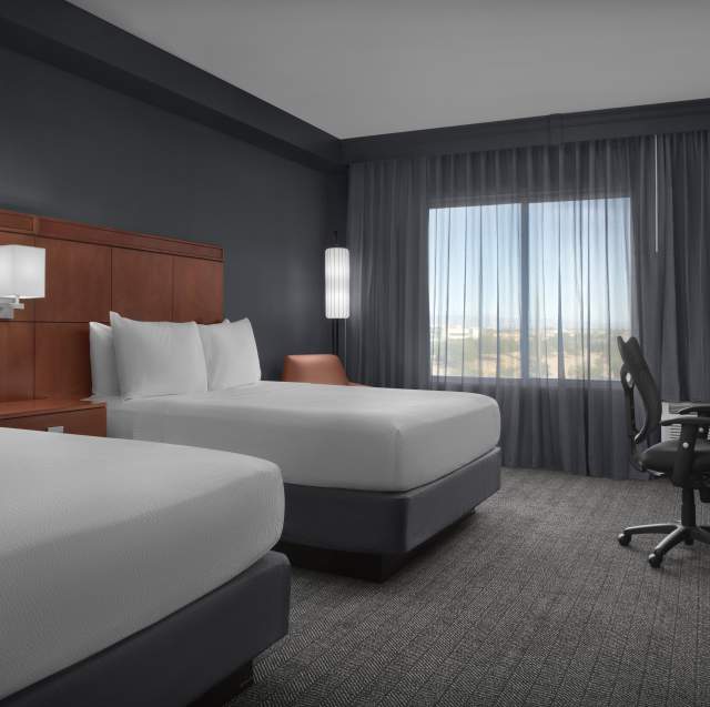 Courtyard by Marriott Phoenix Chandler/Fashion Center guest room with two queen beds, a desk with chair, and a dresser.
