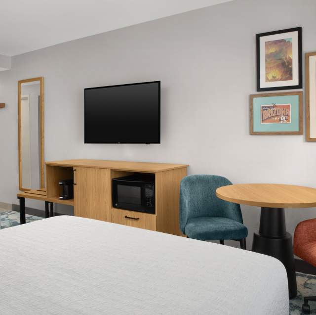 Hampton Inn & Suites Phoenix Chandler-Fashion Center guest room with two queen beds, television, a table, and Arizona cactus photos on the wall.