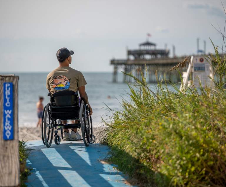 a man in a wheelchair looking at the Cherry Grove Pier