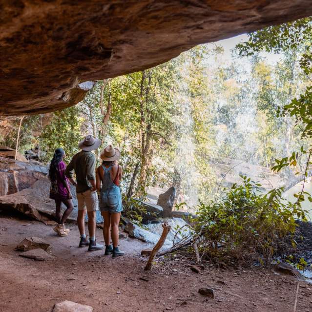 A tour guide stands with two tour guests looking out at a waterfall