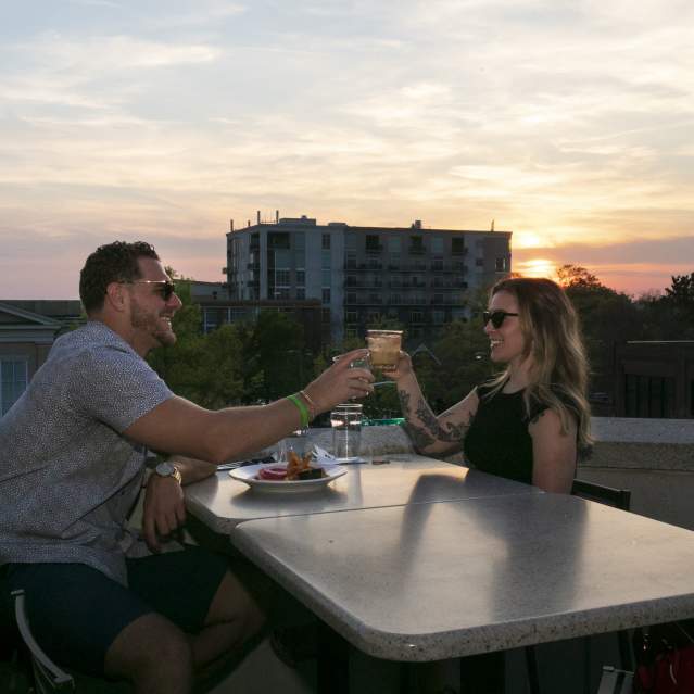 Couple having drinks outside at sunset at Top of the Hill Restaurant