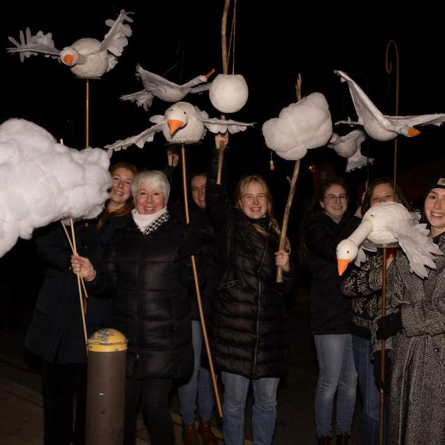 People holding handmade lanterns depicting birds and clouds for the Solstice Lantern Walk in Hillsborough
