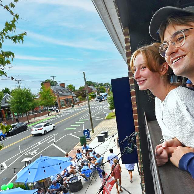 People looking out onto Franklin Street from the upstairs bar at Carolina Brewery