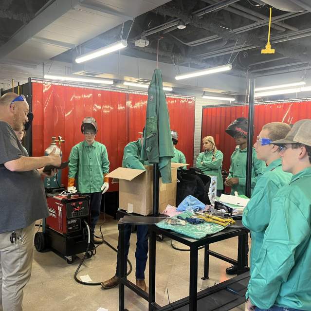 A group of students listen to a presentation on welding at Gateway.