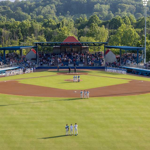 Players and fans standing for national anthem at baseball game