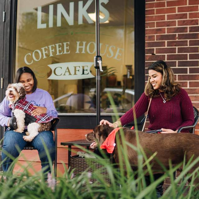 two women with their dogs and coffee