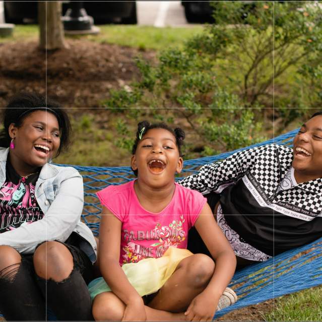 three girls swinging and laughing in a hammock