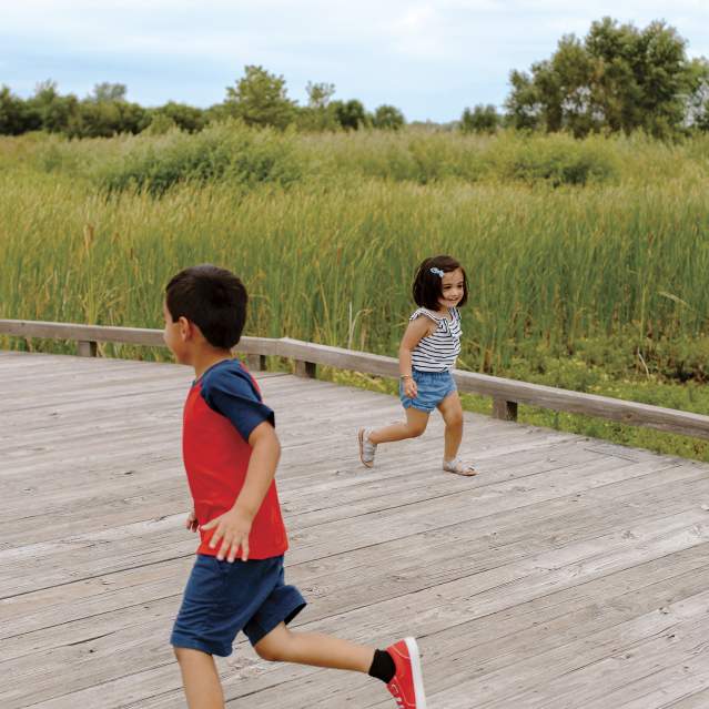 Two kids running around each other on the boardwalk at Glacier Ridge Metro Park