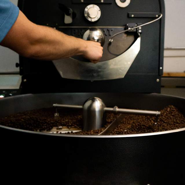 A Honeybee Coffee Co employee works their in-house coffee bean roaster.
