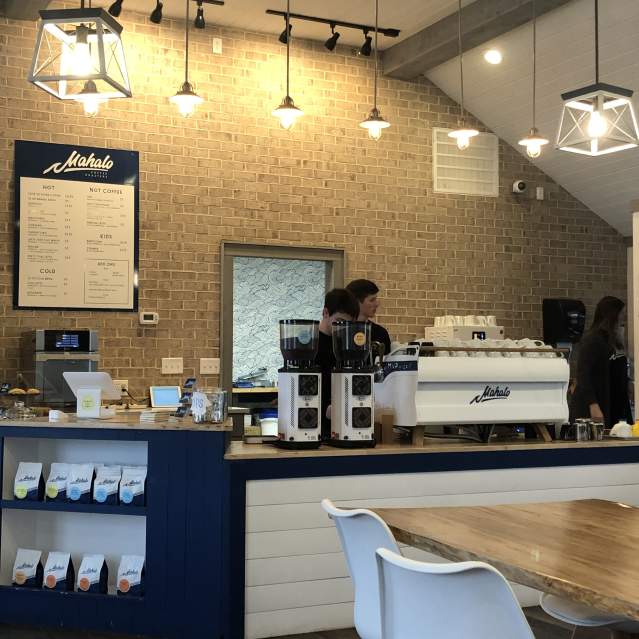 The staff at Mahalo Coffee Roasters work in a well-lit dining area decorated in neutral tones.