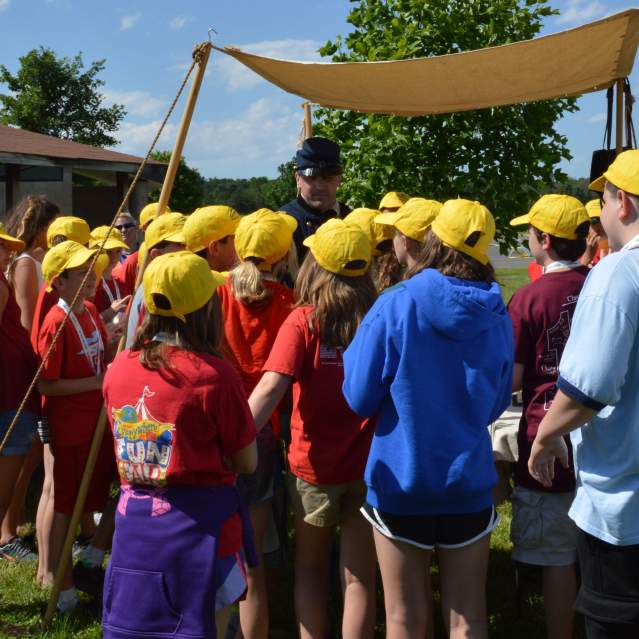 school group on a tour gathered around a historian at the battlefield