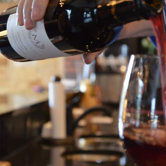 a person pouring a glass of red wine