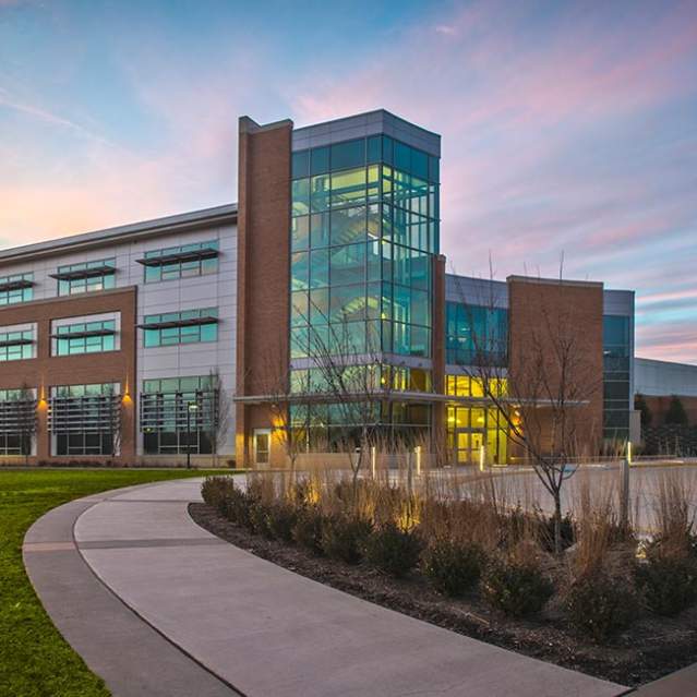 a brick building with many windows at sunset with a walking area in front of the building