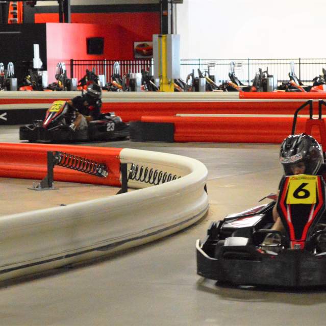 An indoor go-kart facility with 2 go-karters racing