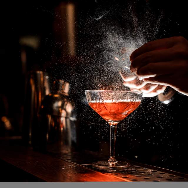 Bartender pouring a red cocktail drink