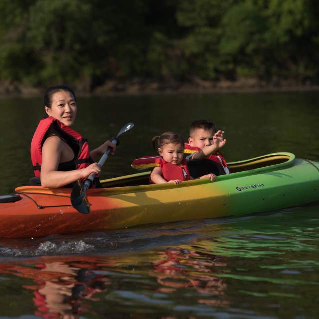 a woman and 2 children kayaking on a river