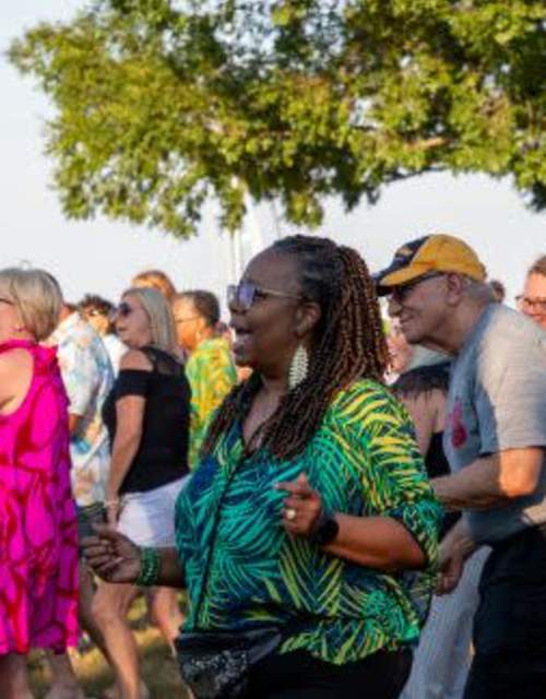Group of partiers dancing outside to live music under a tree