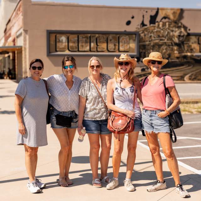 Group of friends posing in front of a colorful Denison mural downtown