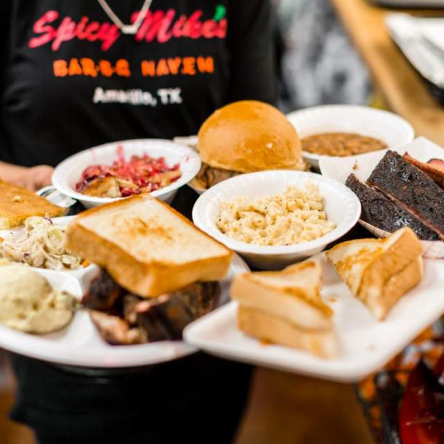 multiple different dishes of texan barbeque being served by a waitress