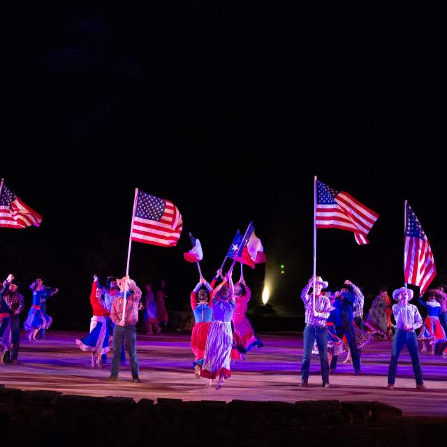Actors on holding texas flags on stage