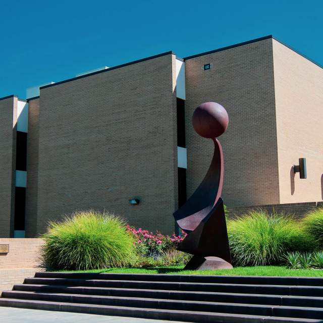 exterior shot of the amarillo museum of arts with blue sky and abstract sculpture in front of the museum