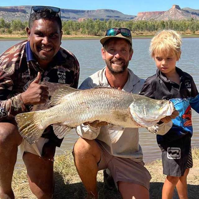 Birchy with a father and son, holding a freshly caught barra