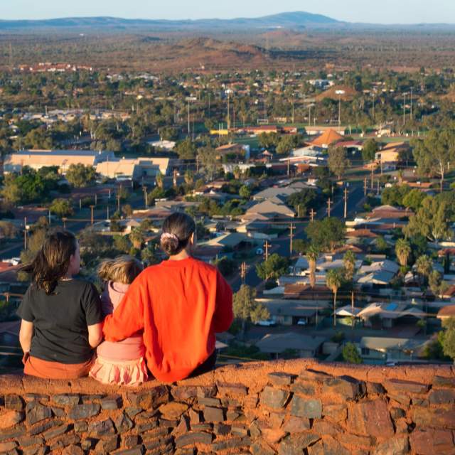 A woman and two children sit at Radio Hill Lookout, looking across the town of Newman