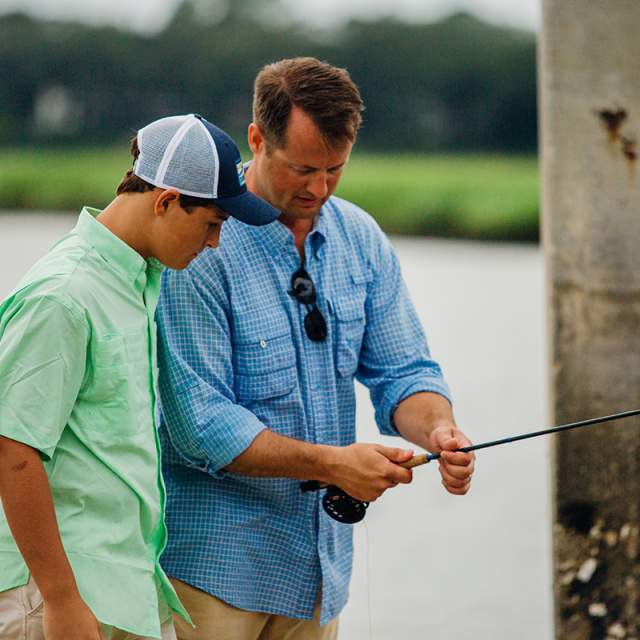 Father Teaching His Son How To Fish