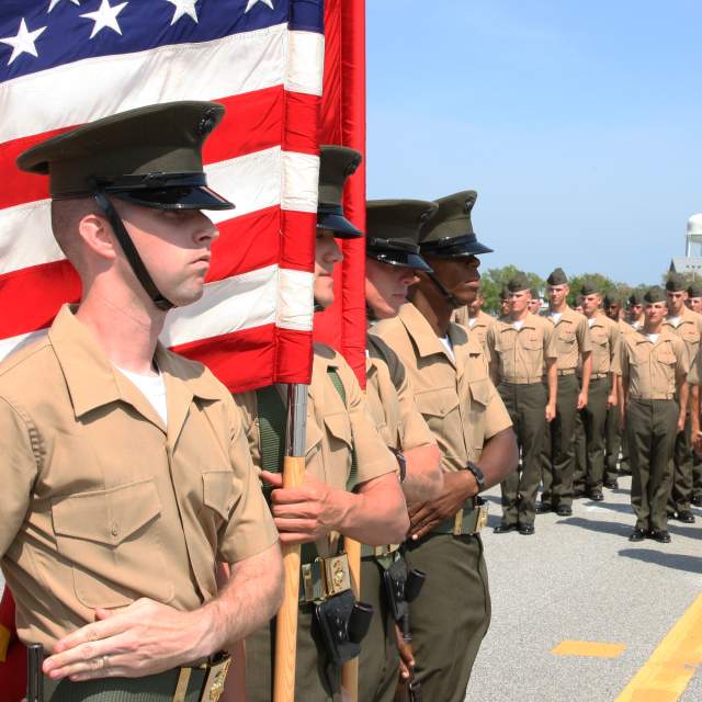 Military personnel standing in formation with American flag