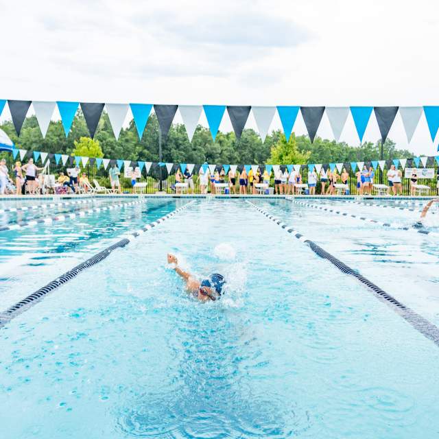 Young girl swimming at a swim meet.