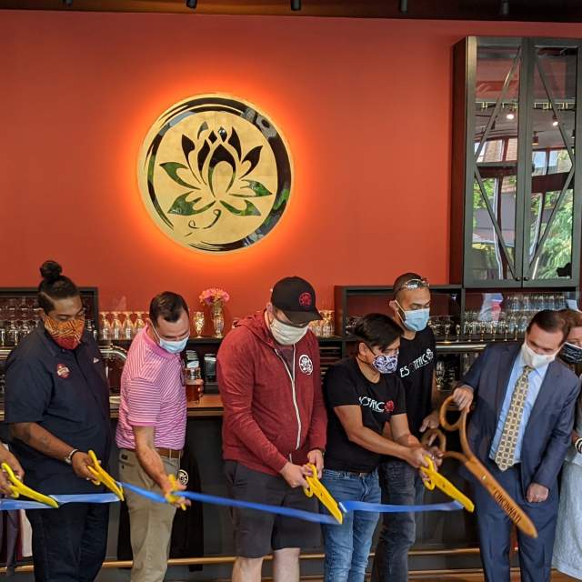 A line of people cutting a ribbon for the opening of Esoteric Brewing in Cincinnati