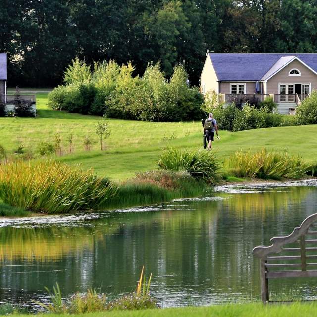 Wakes Hall Lodges with fishing lake and bench in the foreground