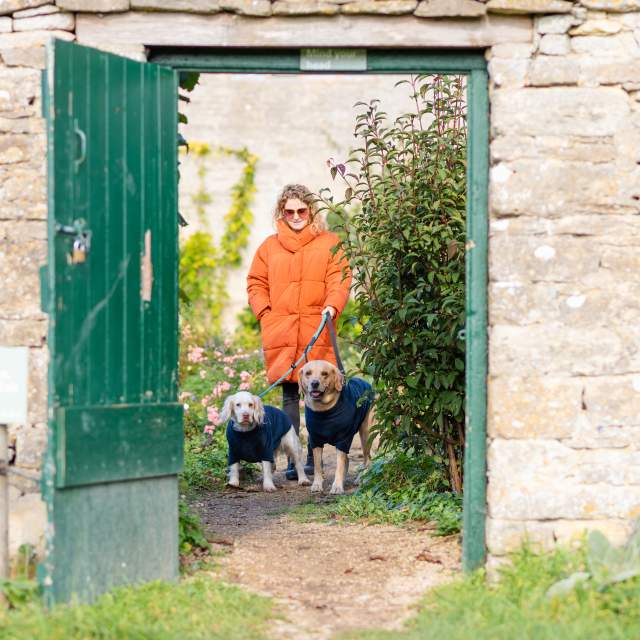 Woman and dogs walking out of the kitchen garden at Cogges Manor Farm