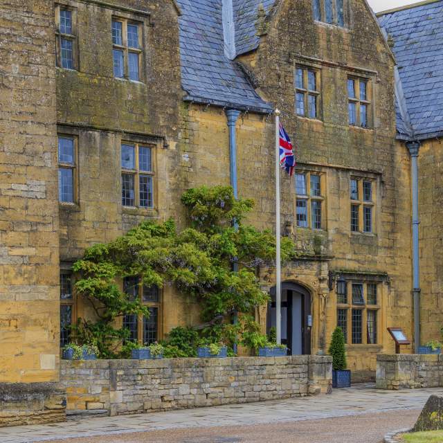 The honey-coloured Lygon Arms, in the Cotswolds, draped in wisteria with Union Jack flags flying