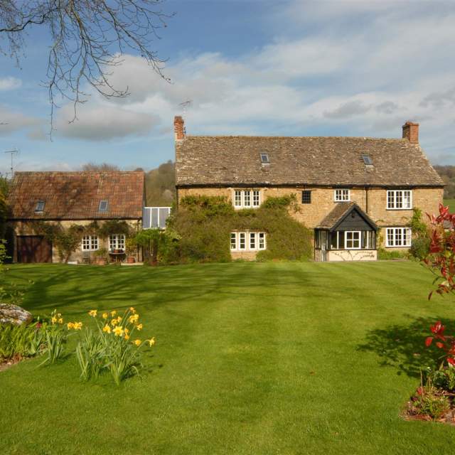 17th Century Cotswold stone farmhouse with open lawn and hedge borders