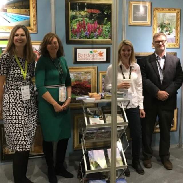 A group of people smile in front of the Cotswolds stand at a show