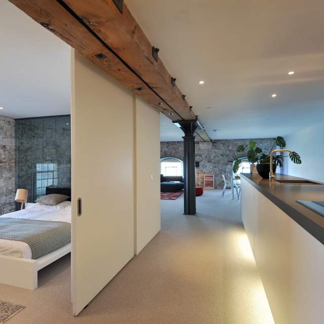 sliding door and a double bed wirh kitchen counter on the right