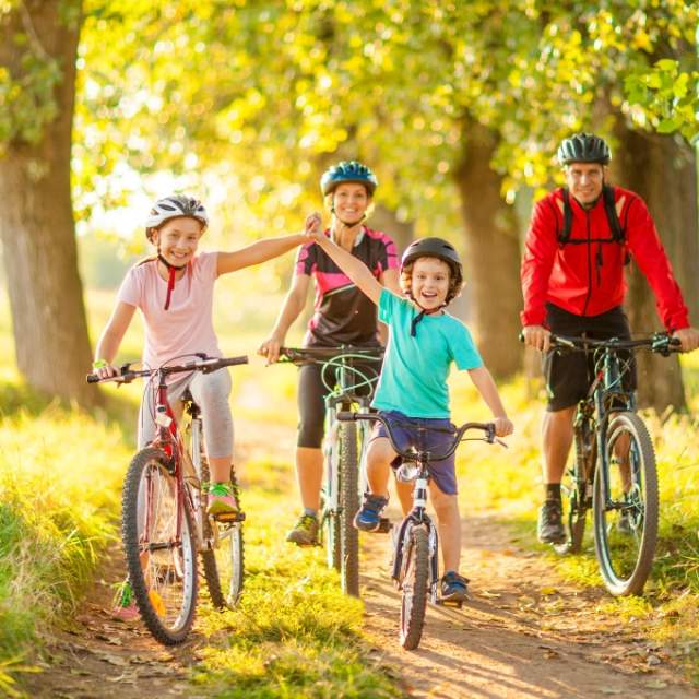 family of four two children at the front cycling on a sunny day
